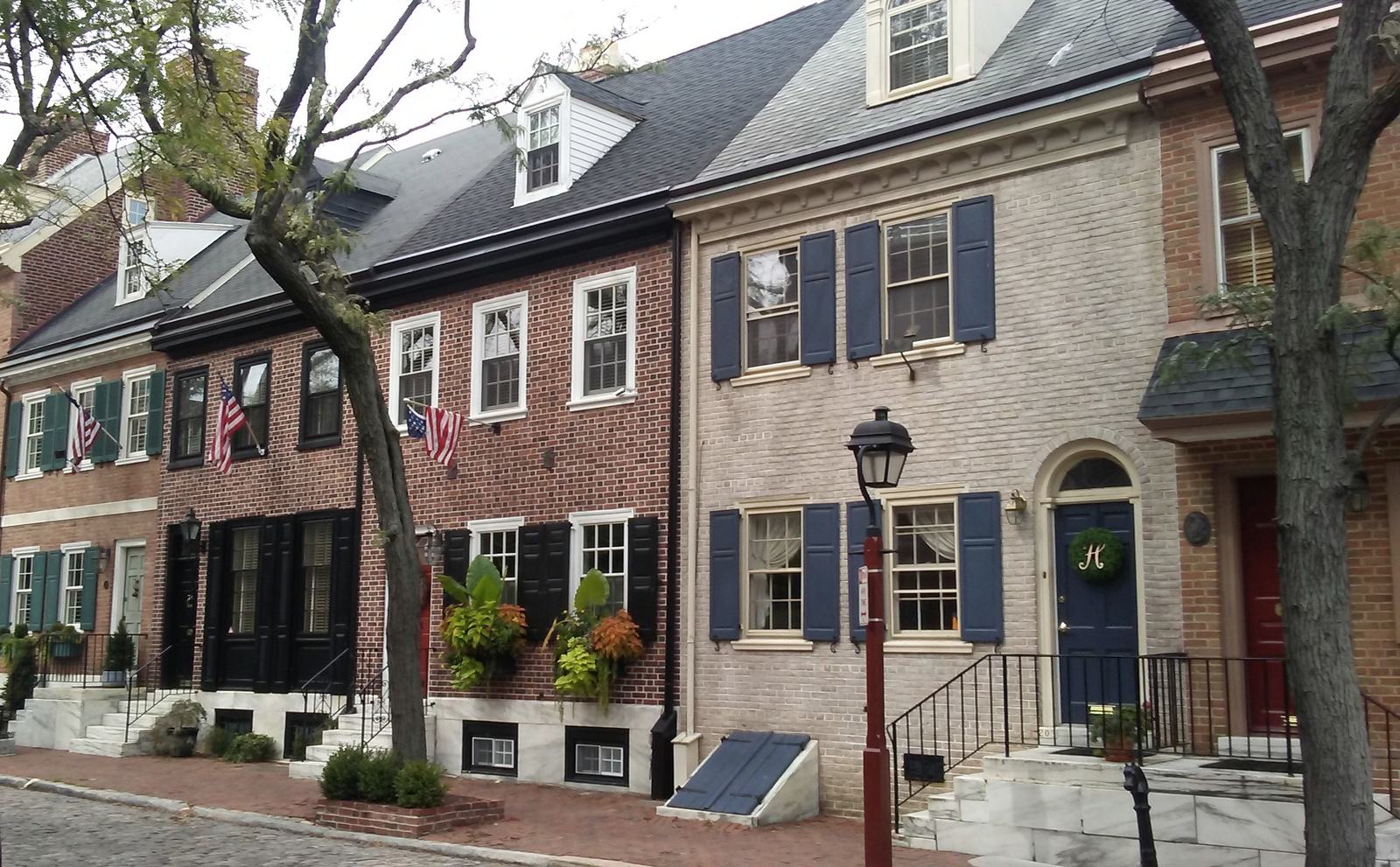 Brick rowhouses with shutters, dormers and marble steps on a tree-lined street
