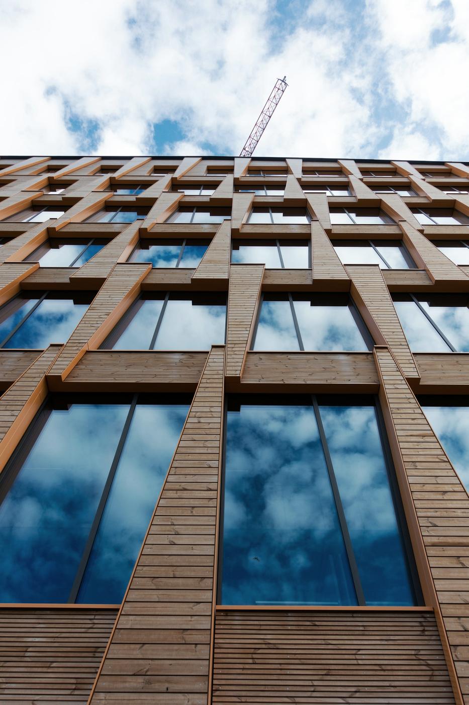 Mass timber high-rise facade under construction with a tower crane