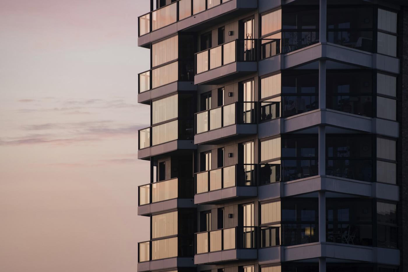 Modern apartment building with glazed balconies at dusk